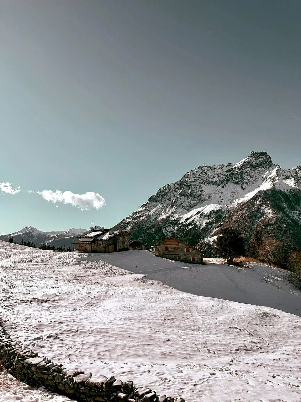 Montagne innevate e un campo di neve sotto un cielo grigio, in Valmalenco