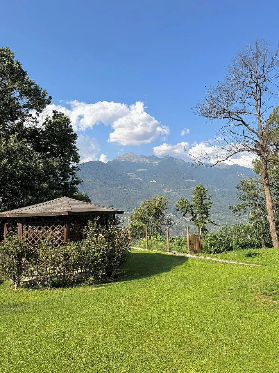 Un prato con un gazebo di legno e le montagne della valle sullo sfondo